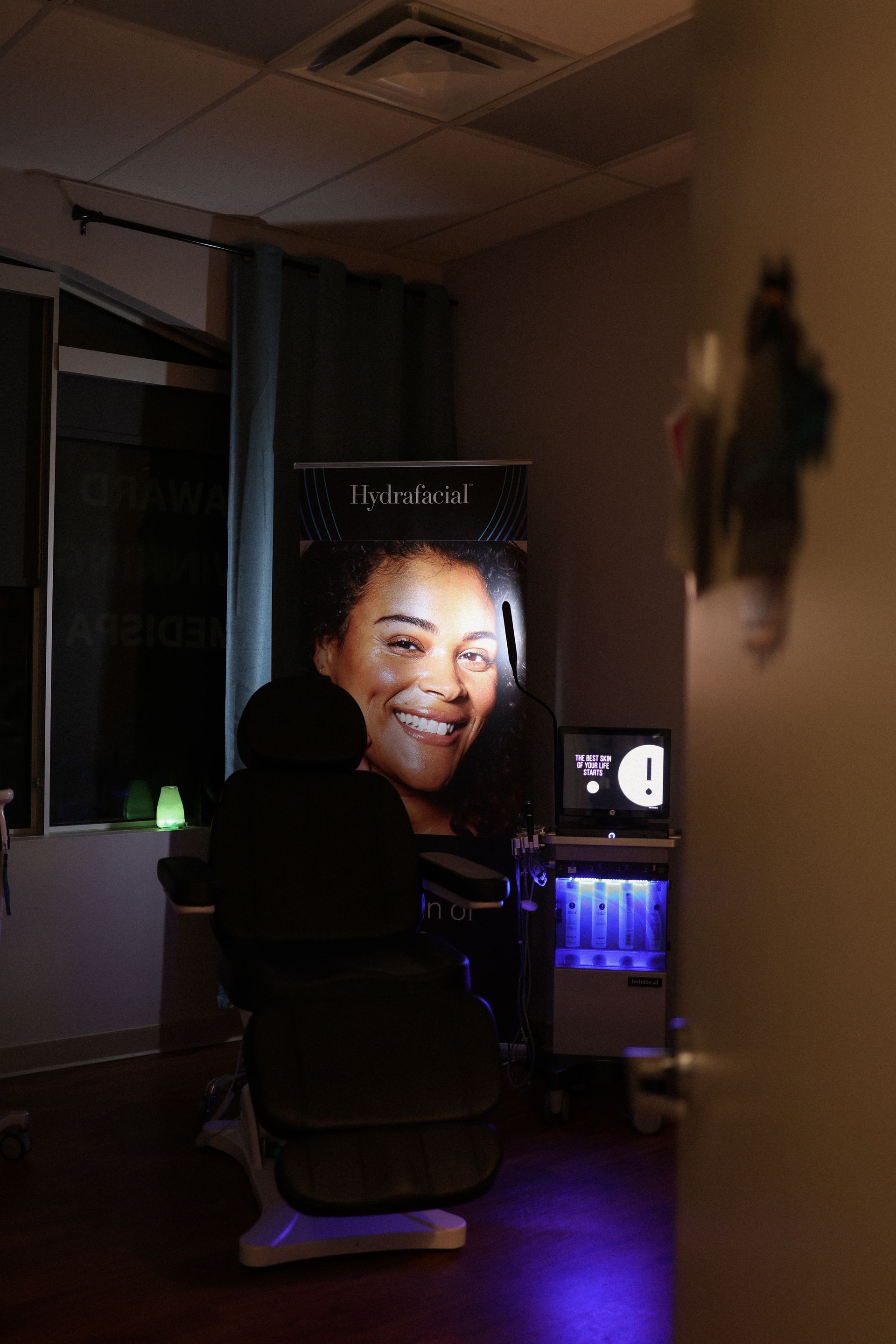 Medical room with aesthetic equipment, a chair, and a display with a smiling face.