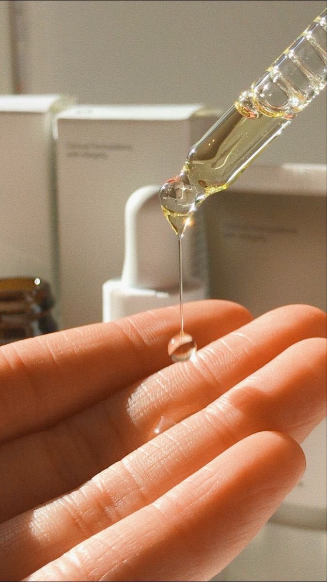 Clear liquid drops from a dropper onto a person's open palm.