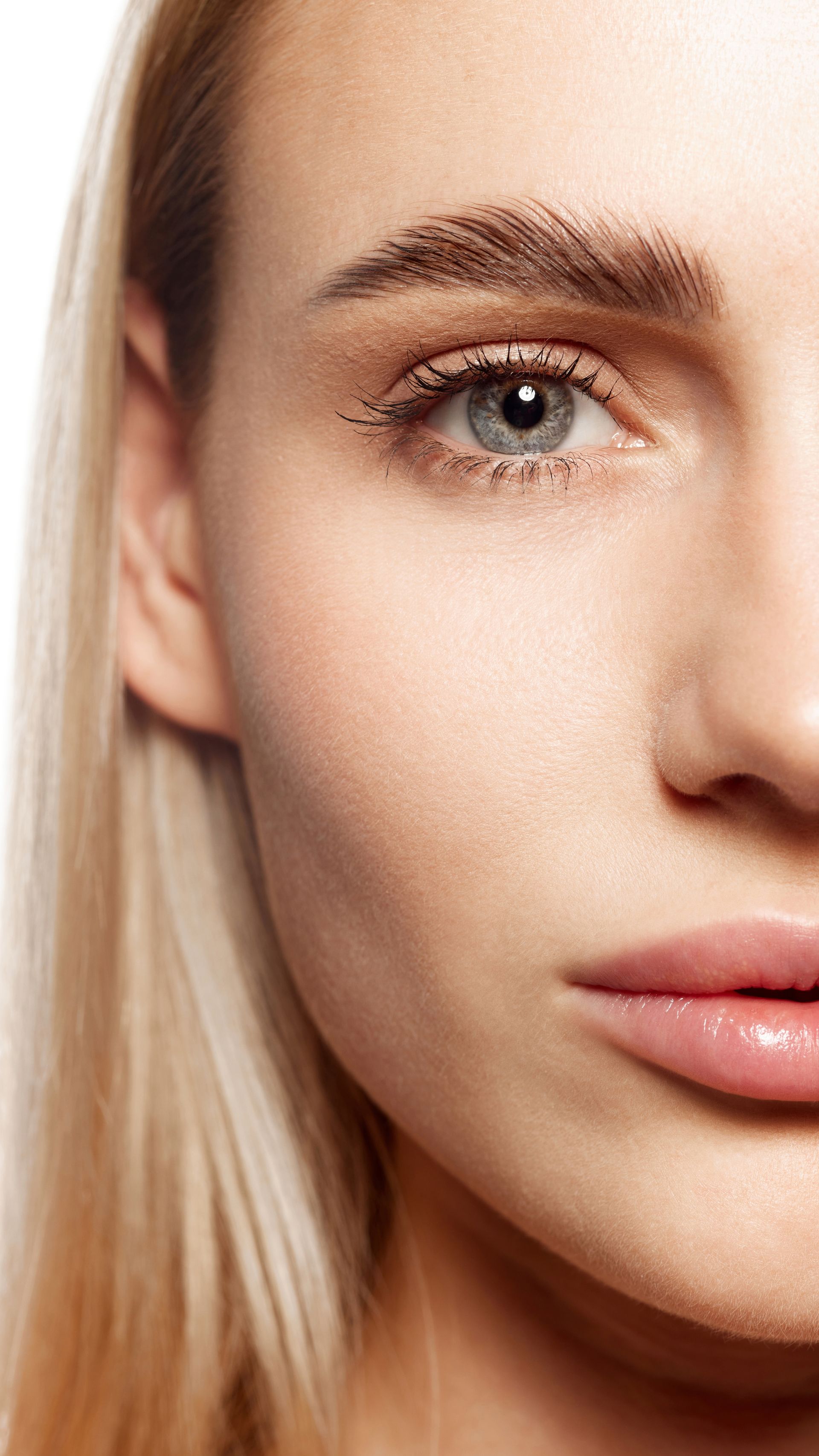 Close-up of a woman's face; fair skin, blonde hair, light eye, defined brows, and neutral makeup.