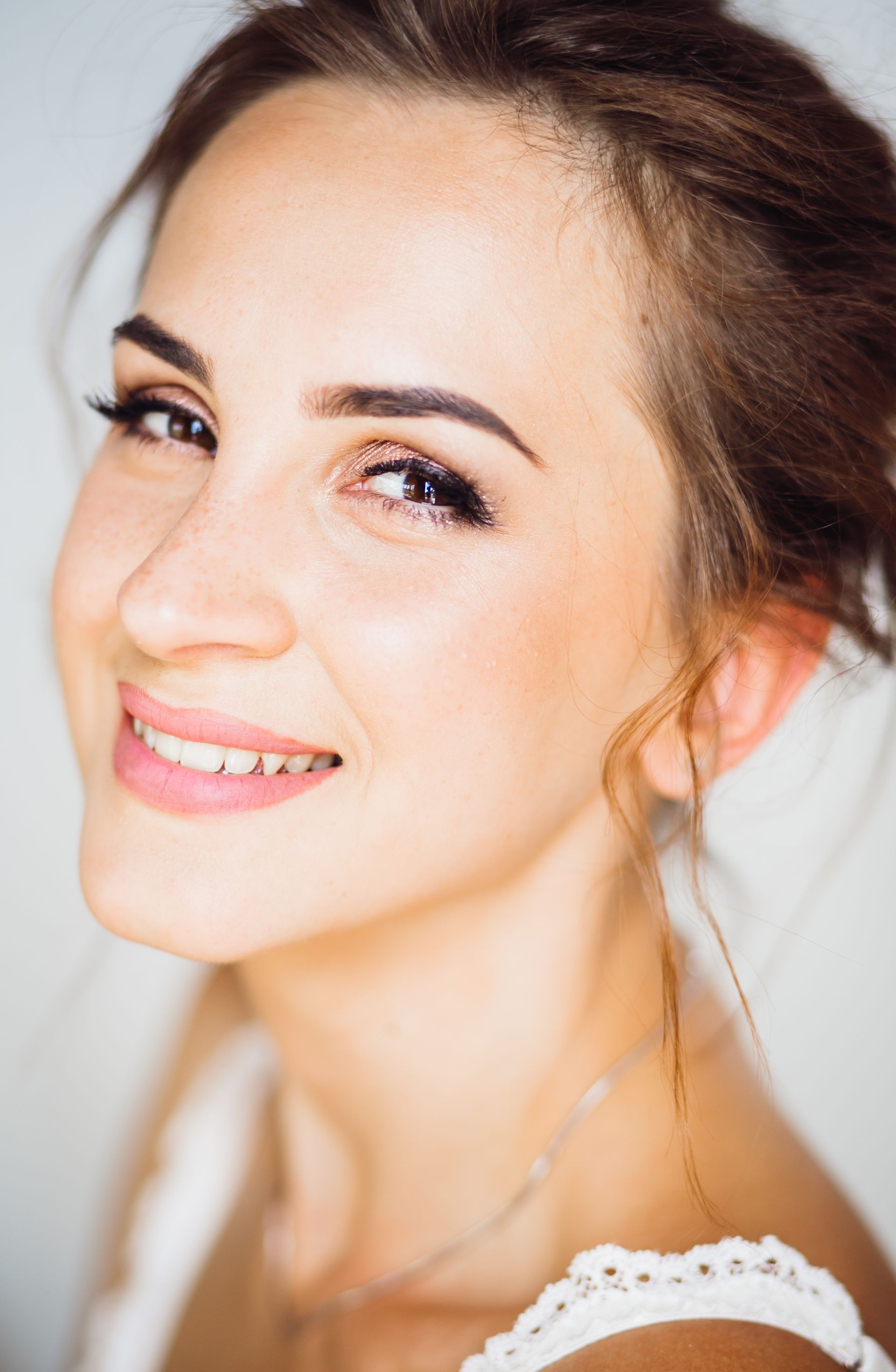 Woman with brown hair smiles at the camera, wearing light makeup.