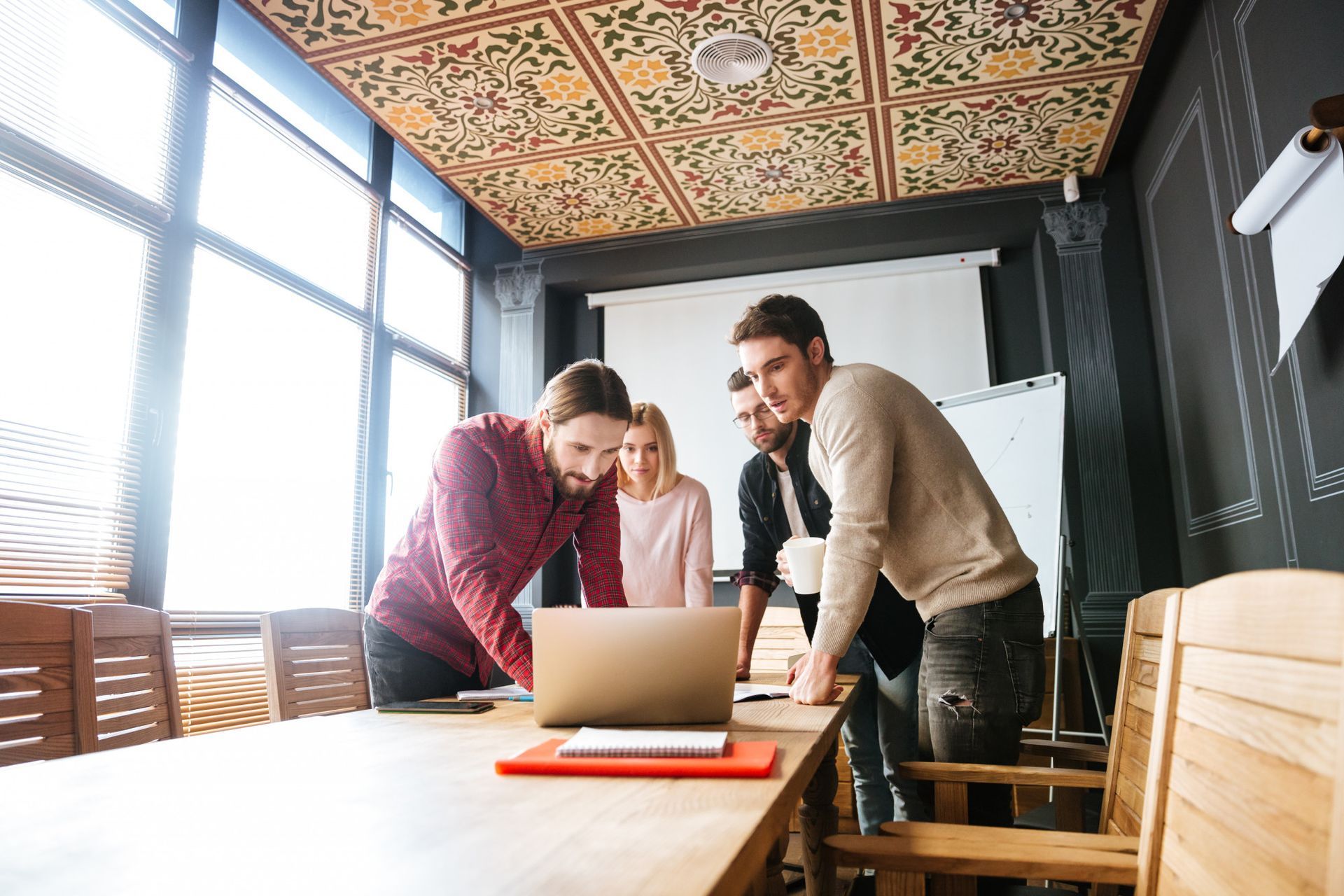 Two women working together, analyzing data on a tablet. One points, the other uses a pen near a calculator.