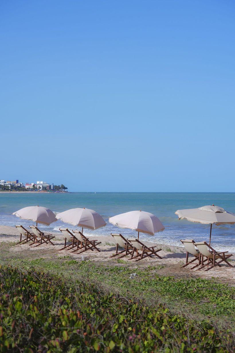 Uma fileira de cadeiras de praia e guarda-sóis em uma praia.