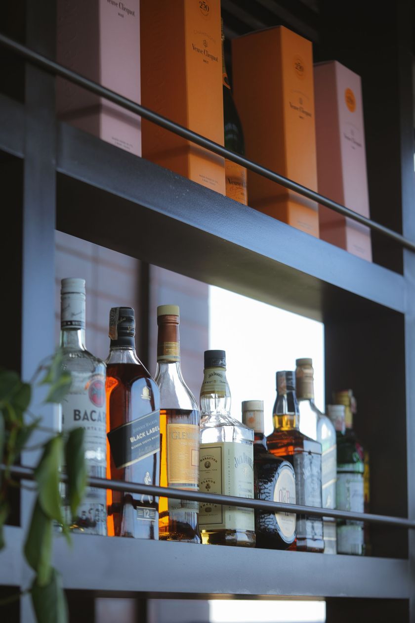 Várias garrafas de álcool estão em uma prateleira, incluindo Bacardi