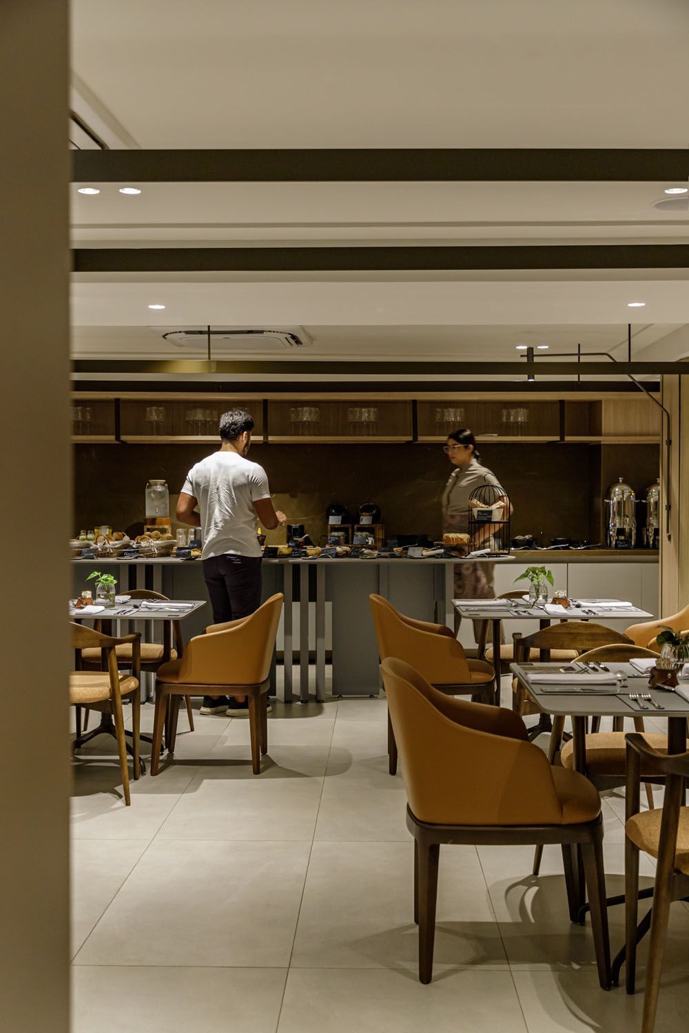 Um restaurante com mesas e cadeiras e uma parede de madeira.