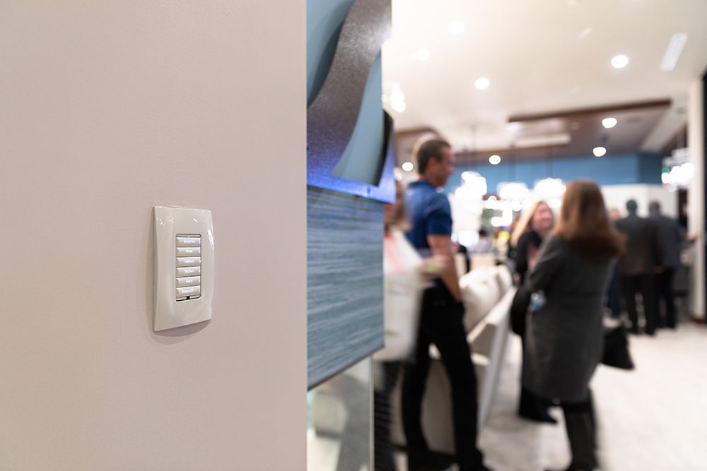 A group of people are standing in a room next to a light switch.