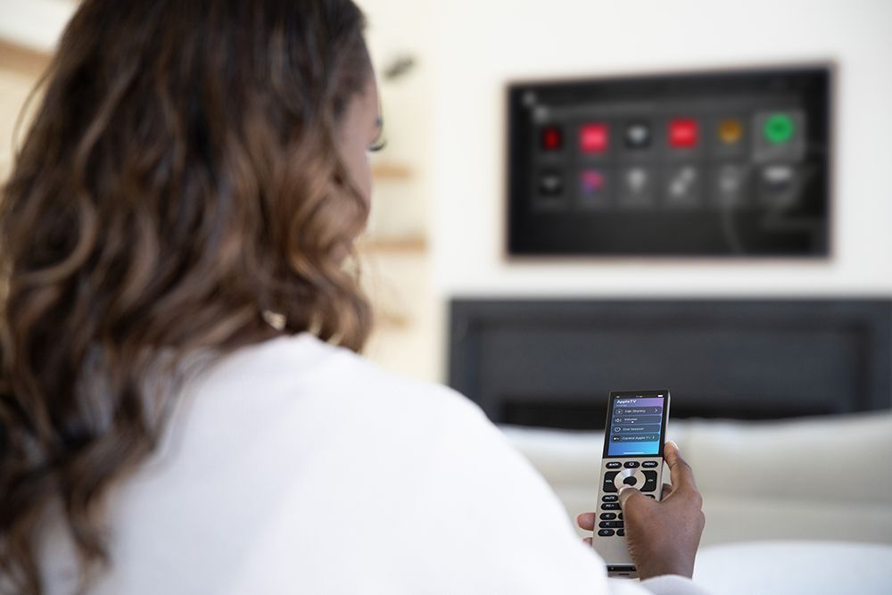 A woman is holding a remote control in front of a television.