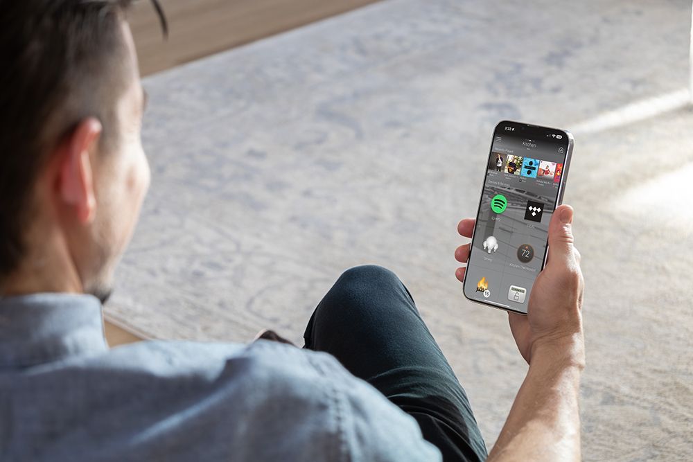A man is sitting on the floor holding a cell phone in his hand.