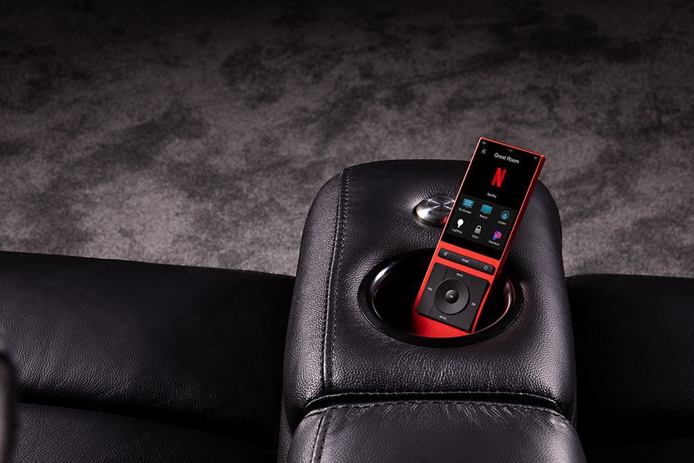 A remote control is sitting in a cup holder on a chair.