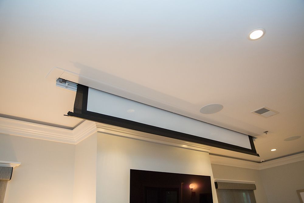 A projector screen is hanging from the ceiling in a living room