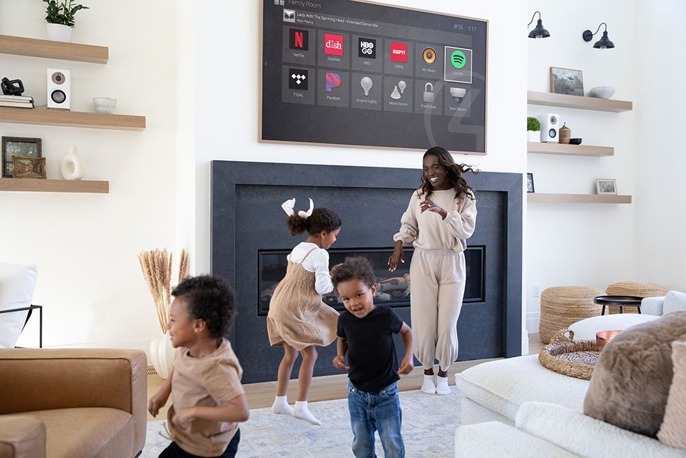 A woman is standing next to two children in a living room.