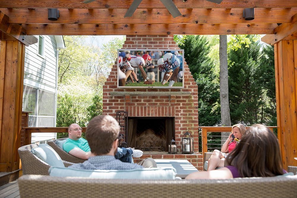 A group of people are sitting in front of a fireplace watching a football game.