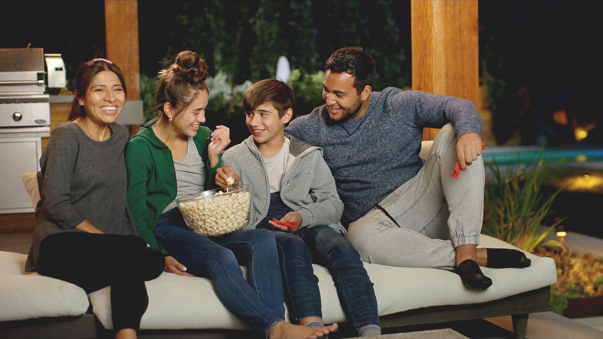 A family is sitting on a couch eating popcorn.