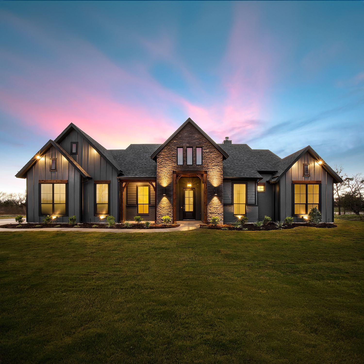 A large house with a lot of windows is sitting on top of a lush green field.