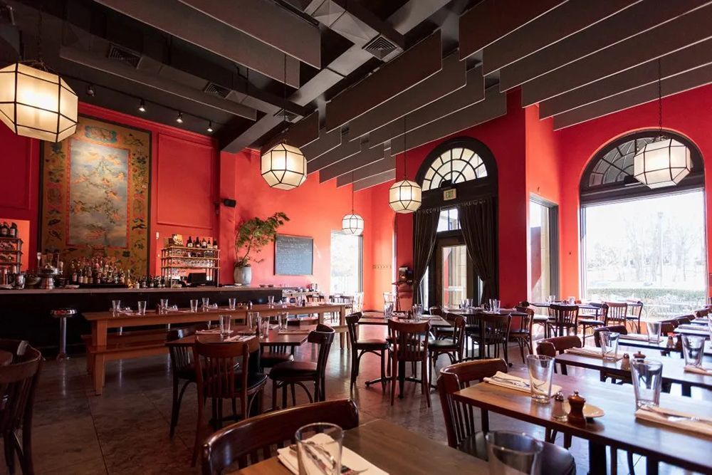 A restaurant with red walls and tables and chairs