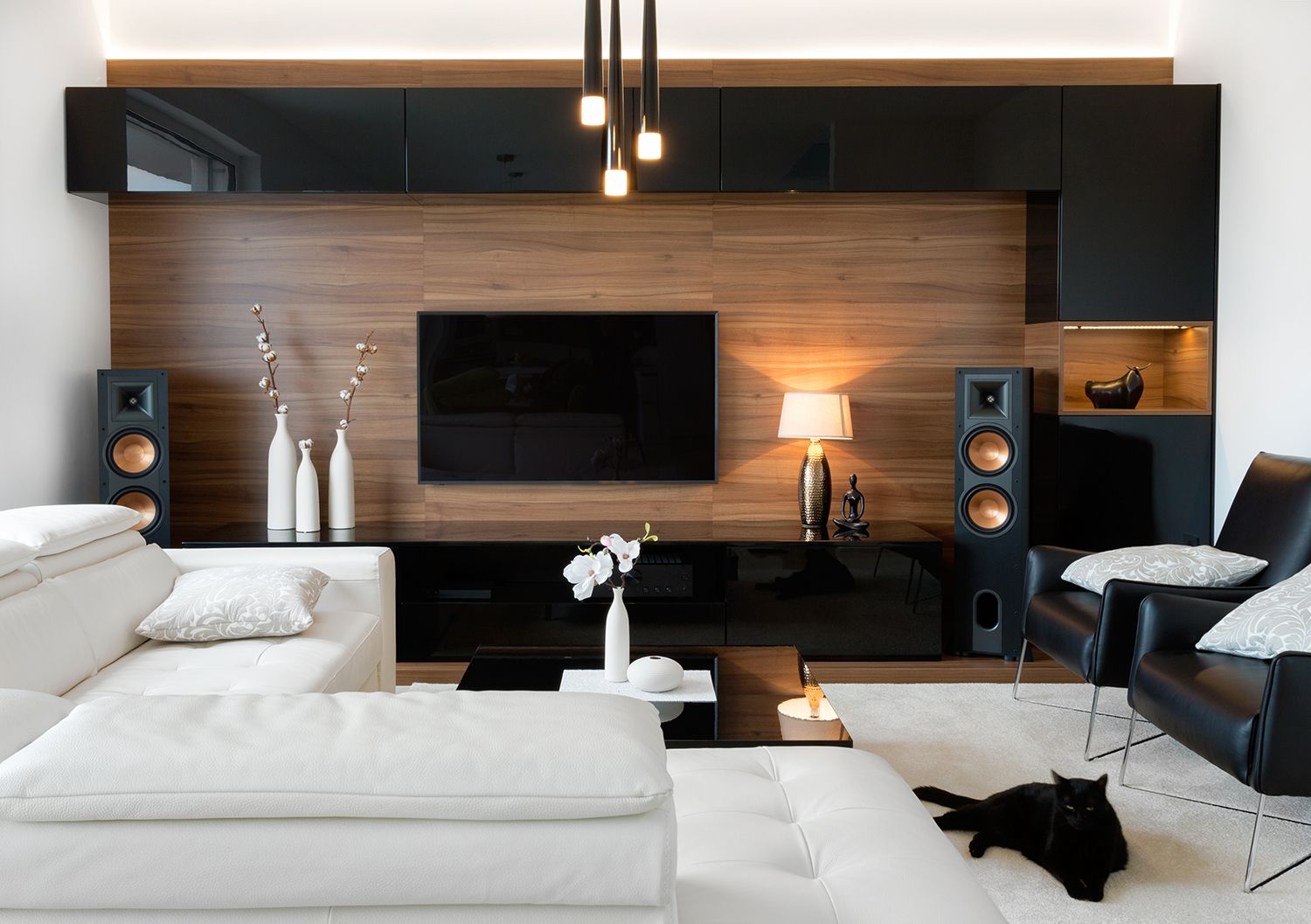 A living room with a couch , chair , speakers and a flat screen tv.