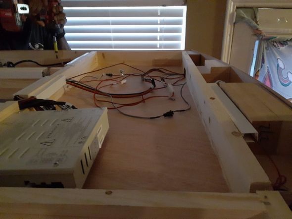 A man is assembling a cabinet in a living room.