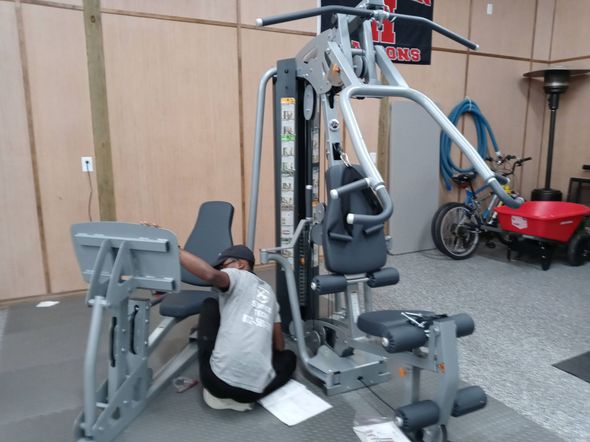 A gym filled with lots of exercise equipment and a wooden floor.