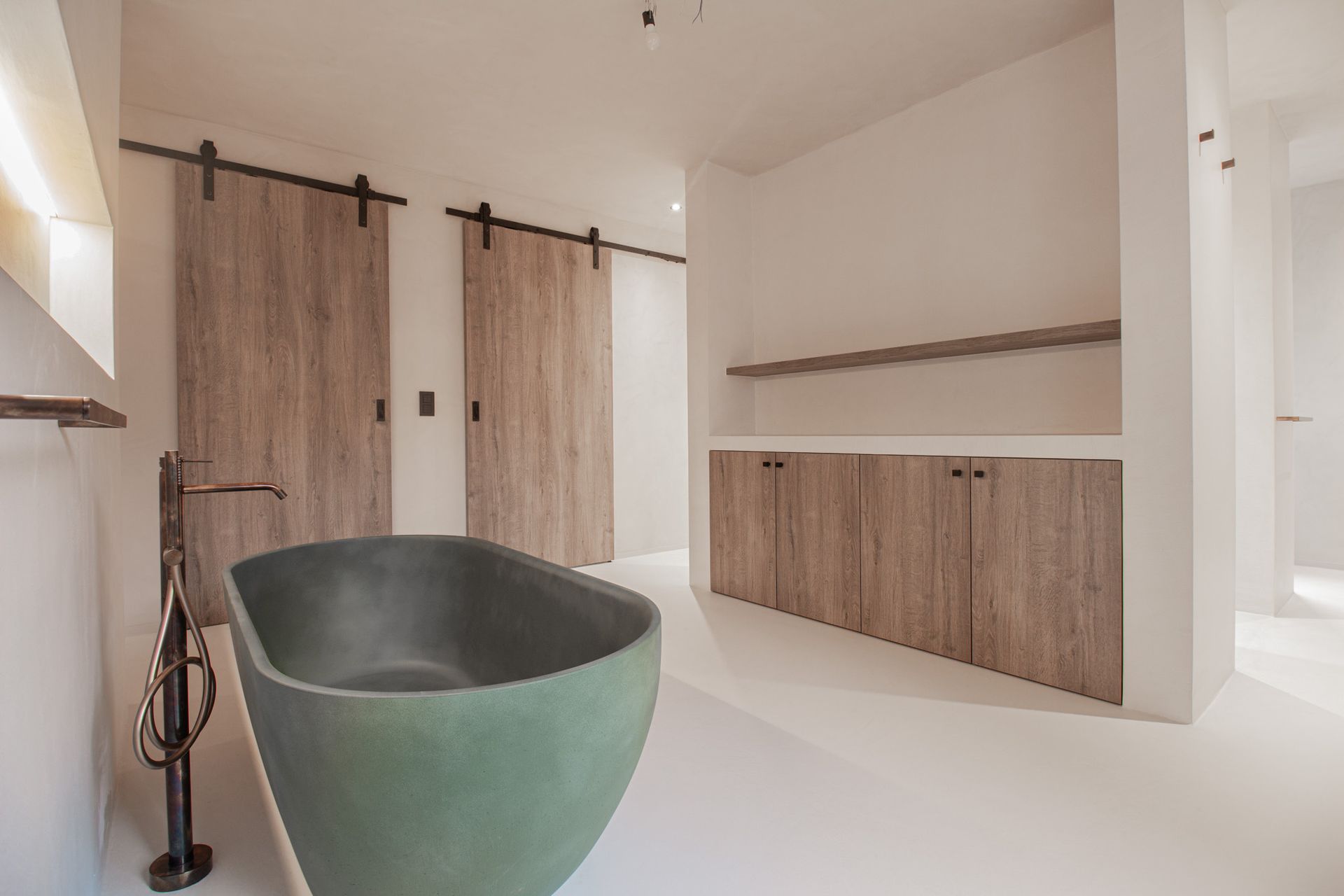 Groen bad, houten schuifdeuren en een minimalistische, witte badkamer.