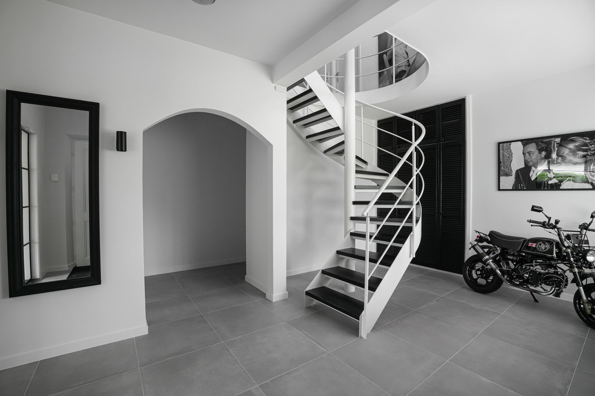 Wenteltrap in een modern huis. Motorfiets en ingelijst kunstwerk.