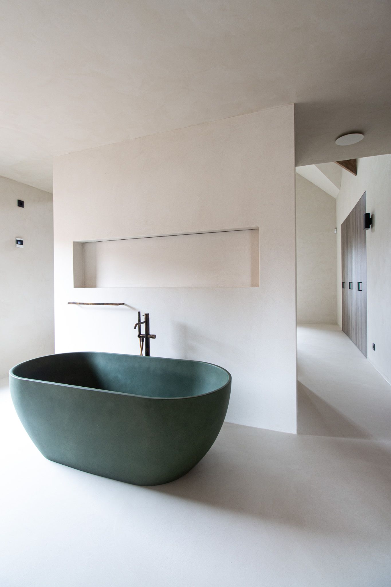 Moderne badkamer met groen ovaal bad tegen witte muur.