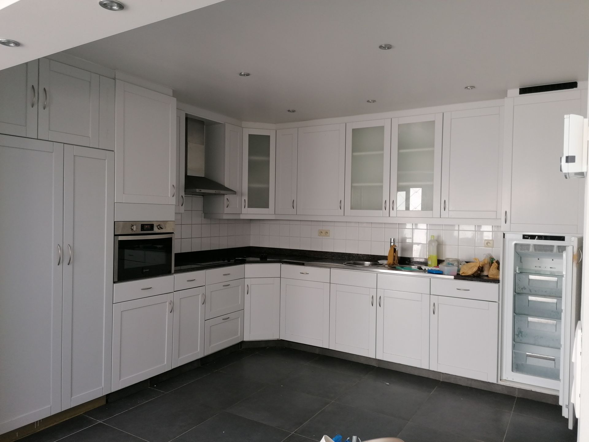 Witte keuken met zwart aanrechtblad en apparatuur.