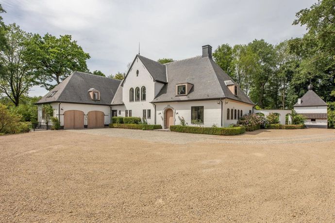 Wit huis met donker dak en grindpad.
