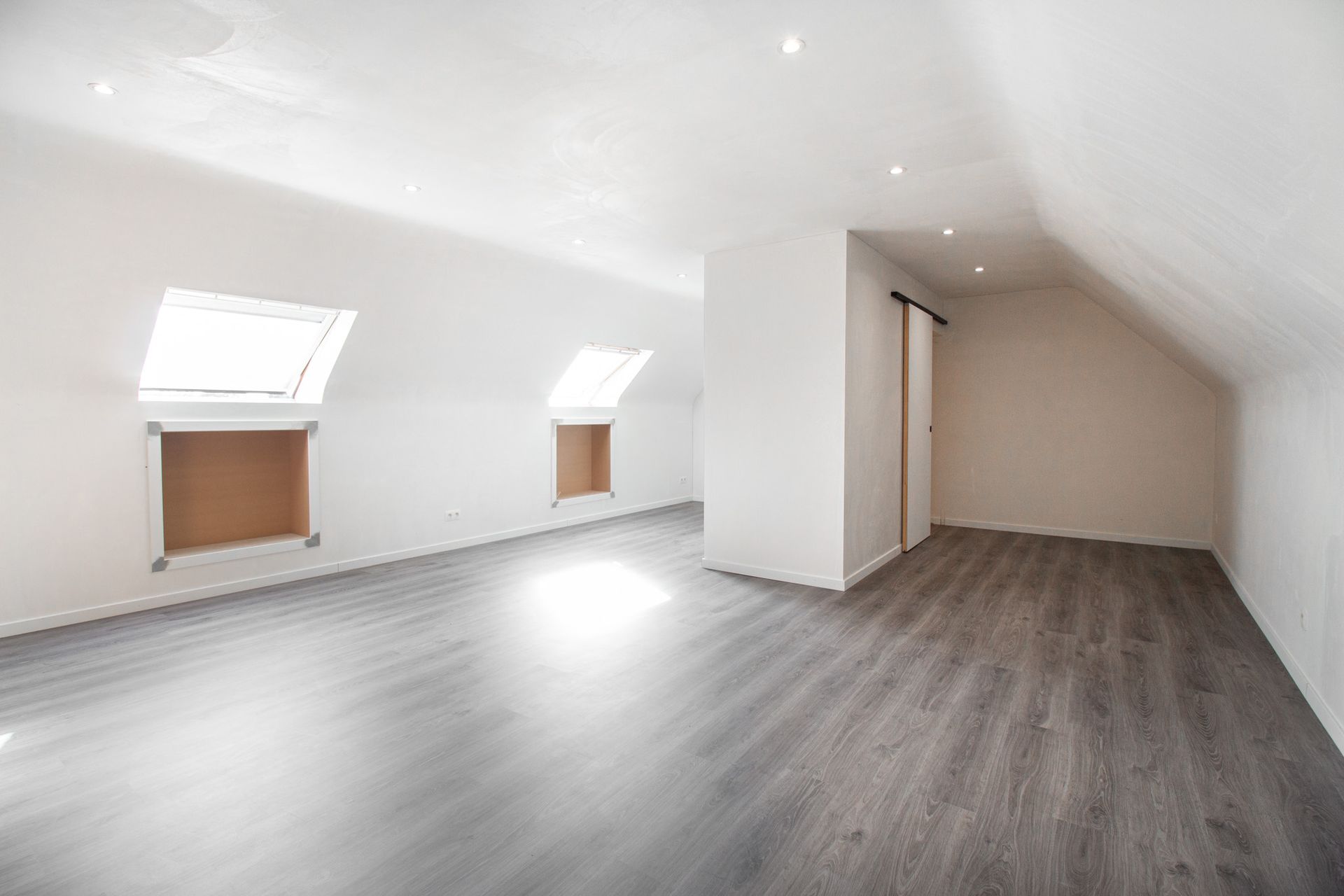 Moderne wachtkamer met bruine stoelen, kleine tafeltjes en kamerhoge ramen met uitzicht op het groen.