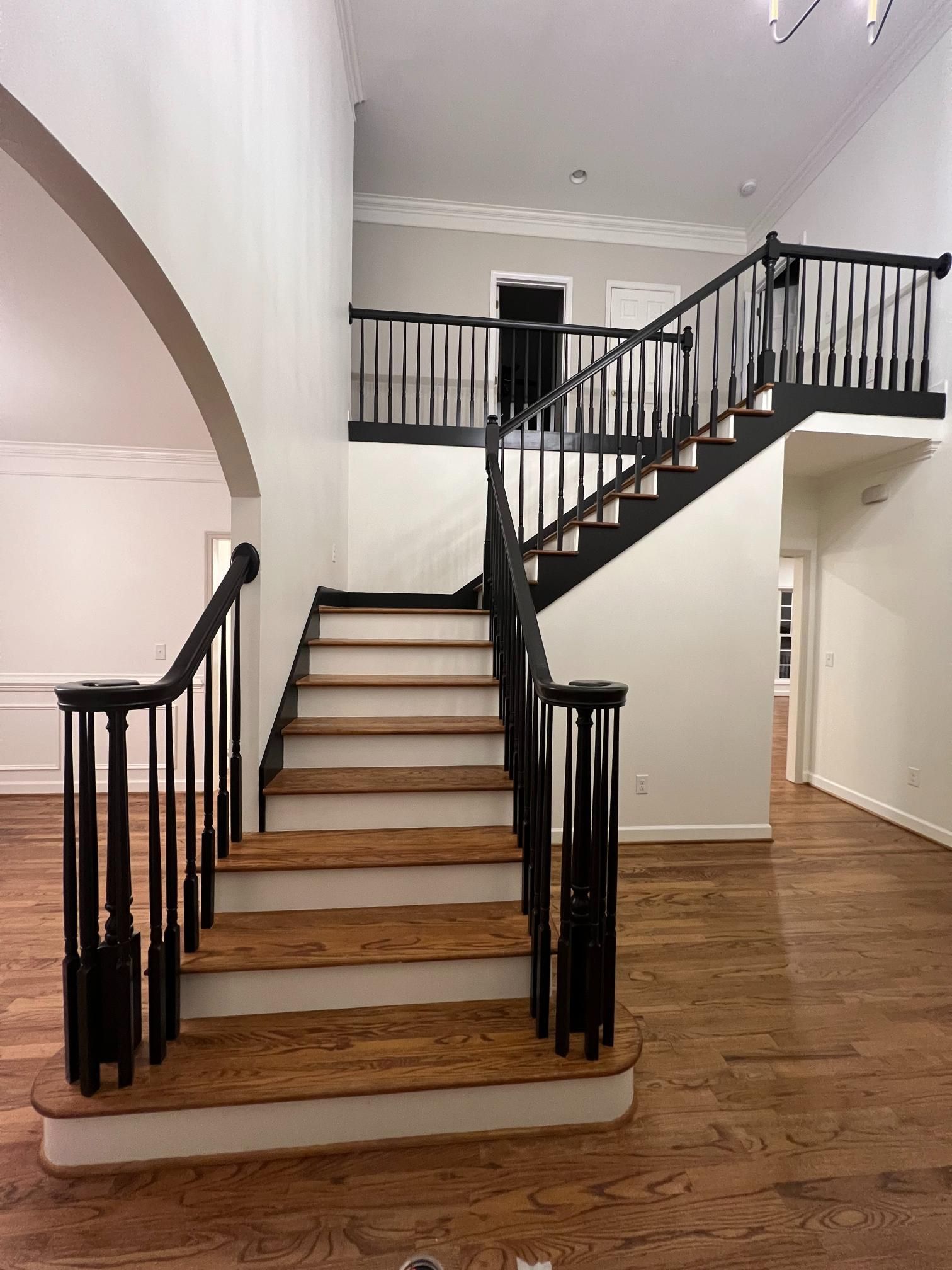 A staircase with dark wood-stained treads and white risers, featuring black railings leading to a second-floor landing.