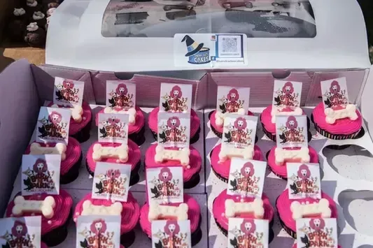 A box of pink cupcakes with dog bones on them