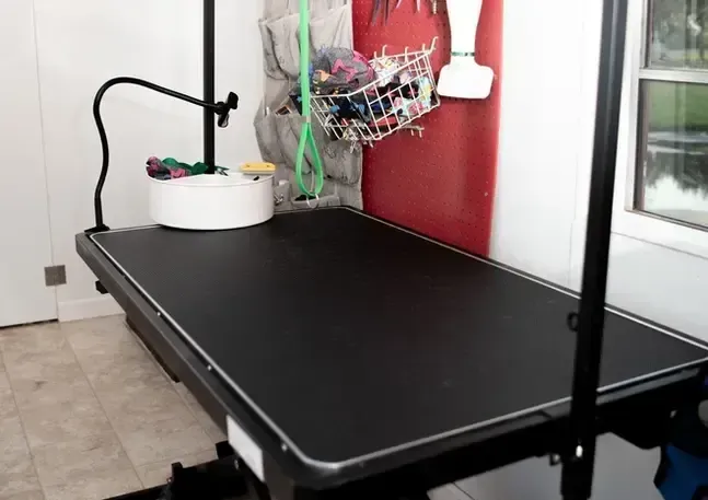 A black dog grooming table with a basket hanging from it
