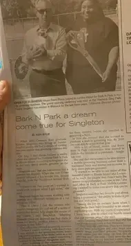 A person is holding a newspaper with a picture of two people standing next to each other.