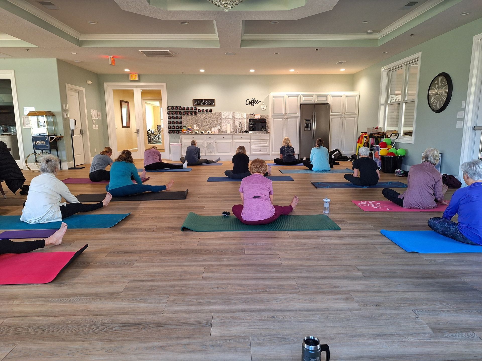 A group of people are sitting on yoga mats in a room.