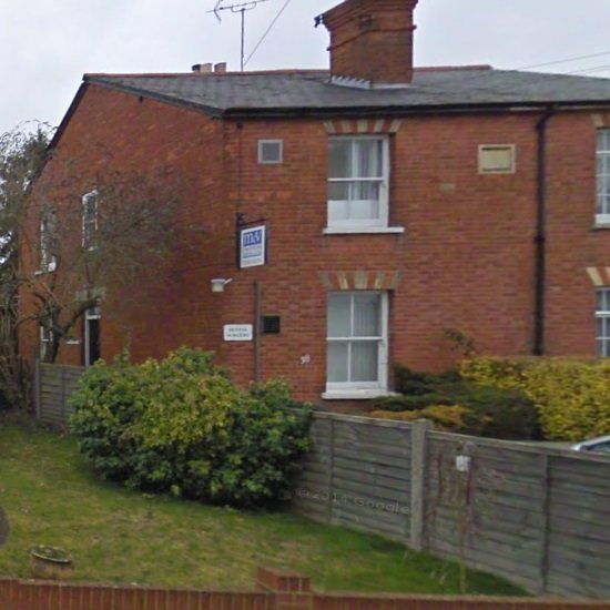 A brick house with a sign on the side that says ' for sale '