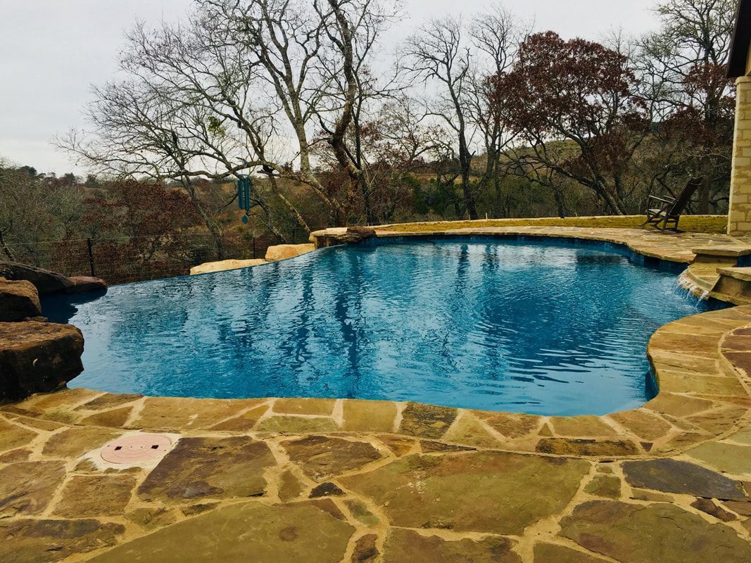 A large swimming pool surrounded by rocks and trees.