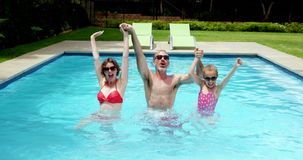 A man , woman and child are standing in a swimming pool.
