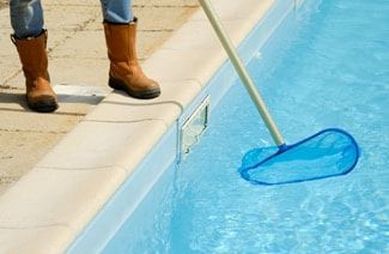 A person is cleaning a swimming pool with a net.
