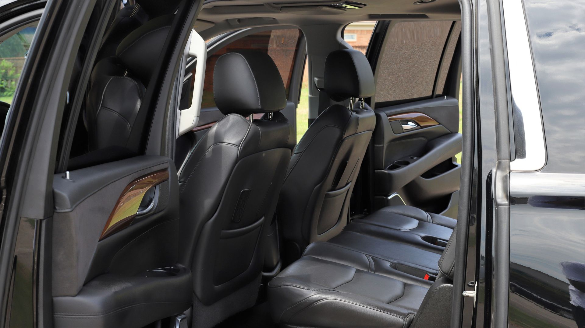 Black SUV interior with leather seats; back row and middle row seats visible, tinted windows.