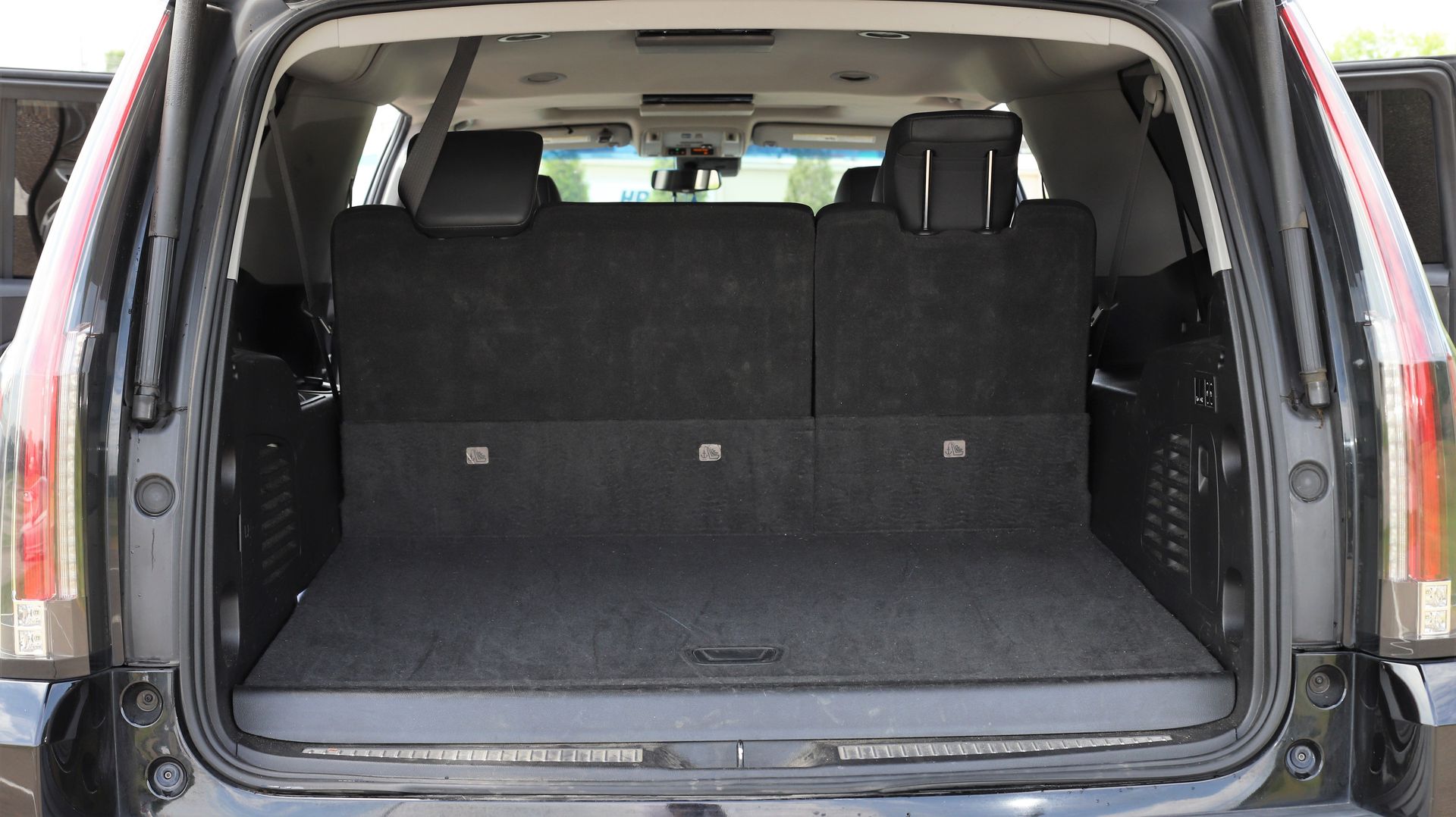 Open cargo area of a black SUV with the back seats folded down, showing a flat, carpeted floor.