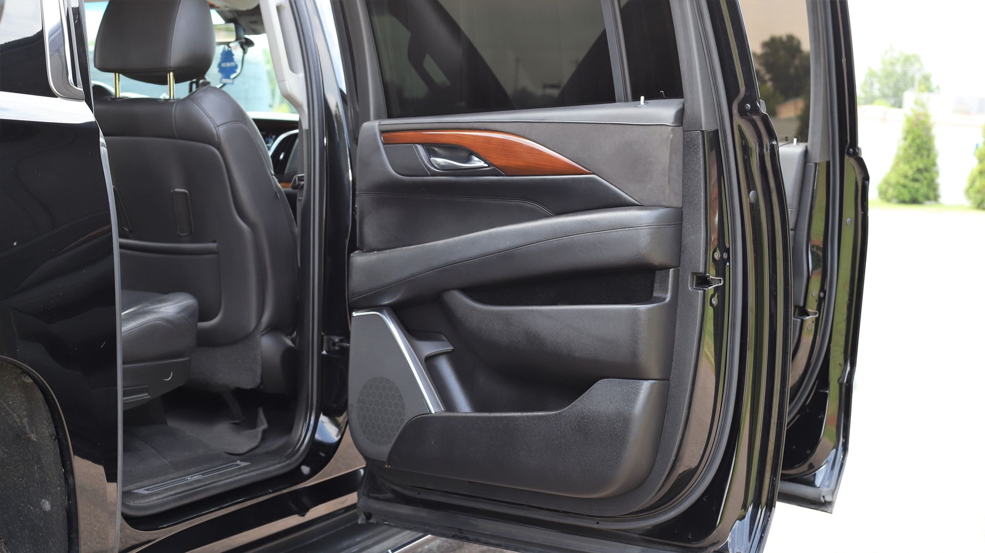 Black car door open, revealing interior with black leather seats and wood trim.