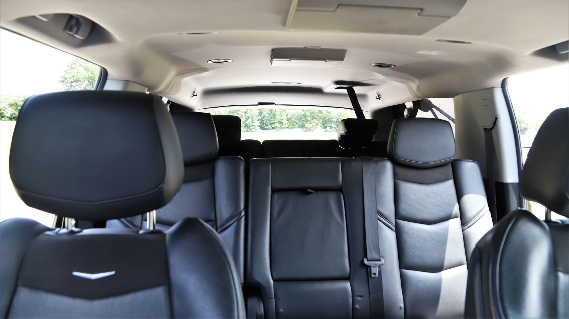 Interior of a black Cadillac SUV, showing rear leather seats and overhead console.