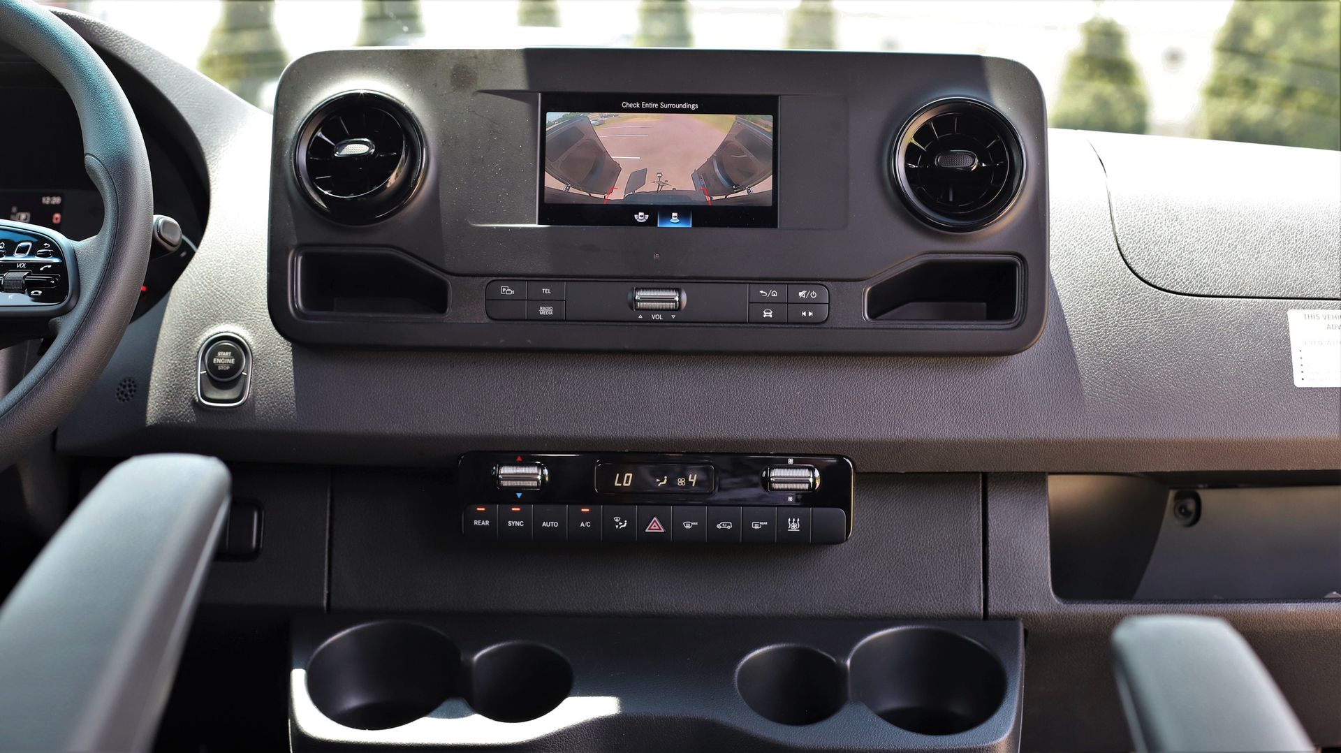 Dashboard of a van with screen displaying a rear camera view, air vents, and controls.