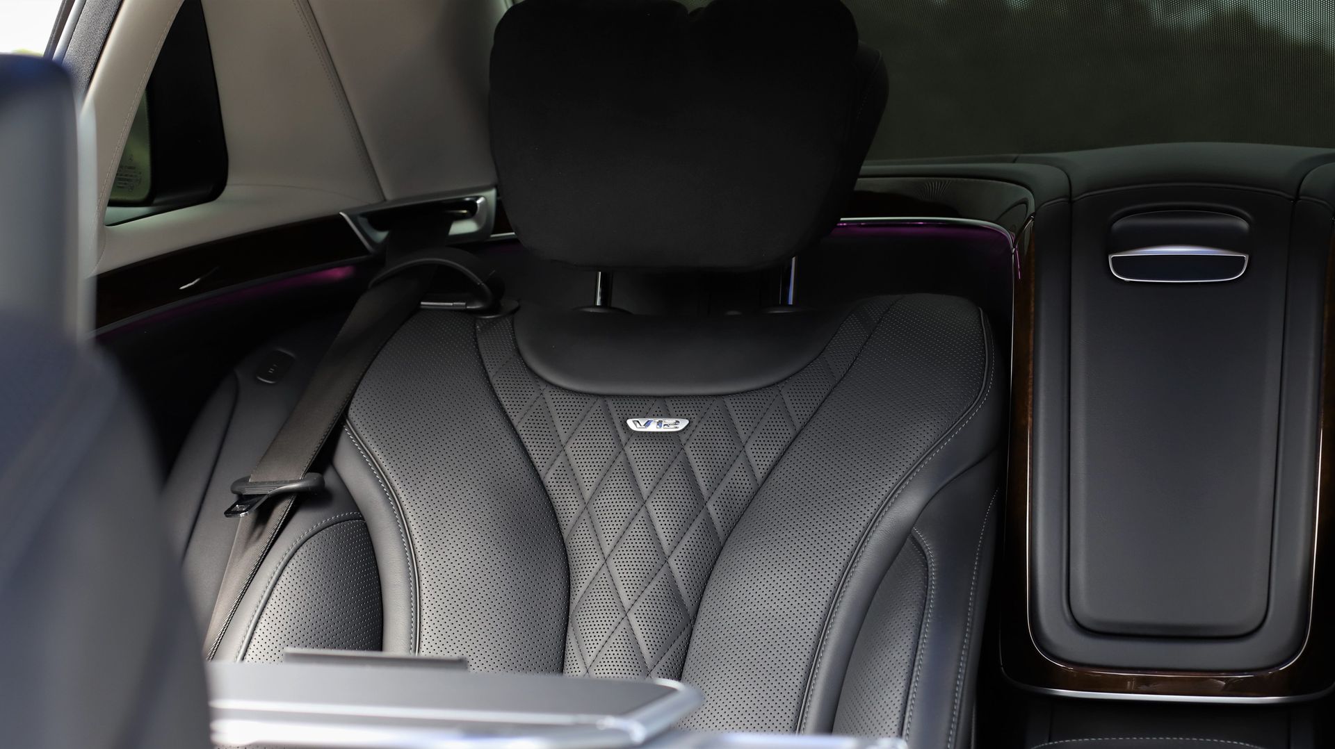 Black leather car seat with headrest, armrest, and tabletop, interior detail.
