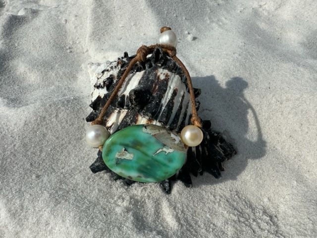A sea shell with a green stone and pearls on it