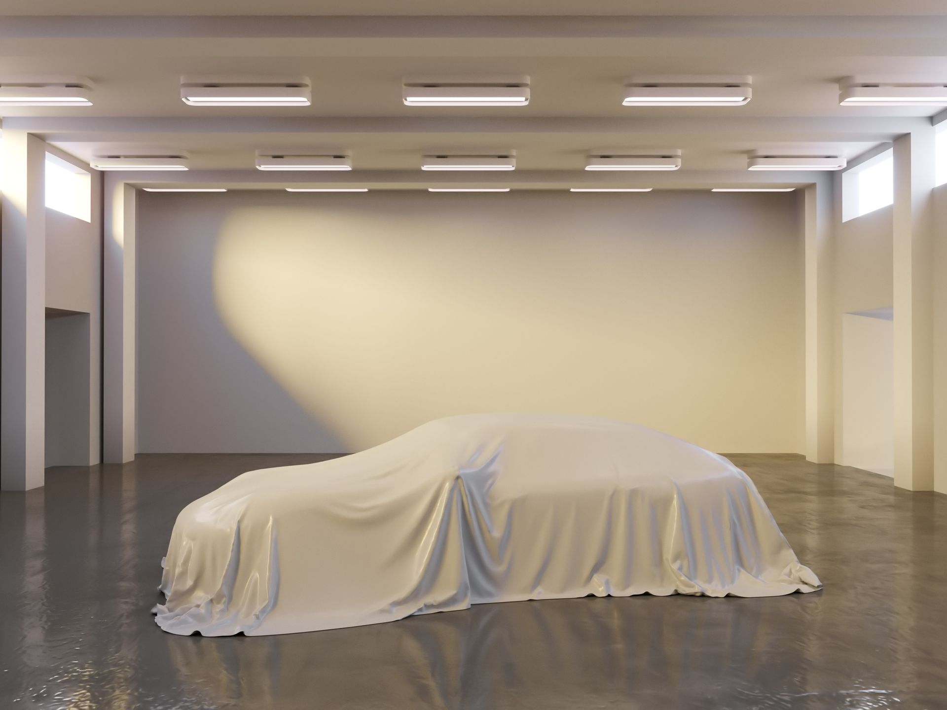 A car is covered in a white cloth in a garage.