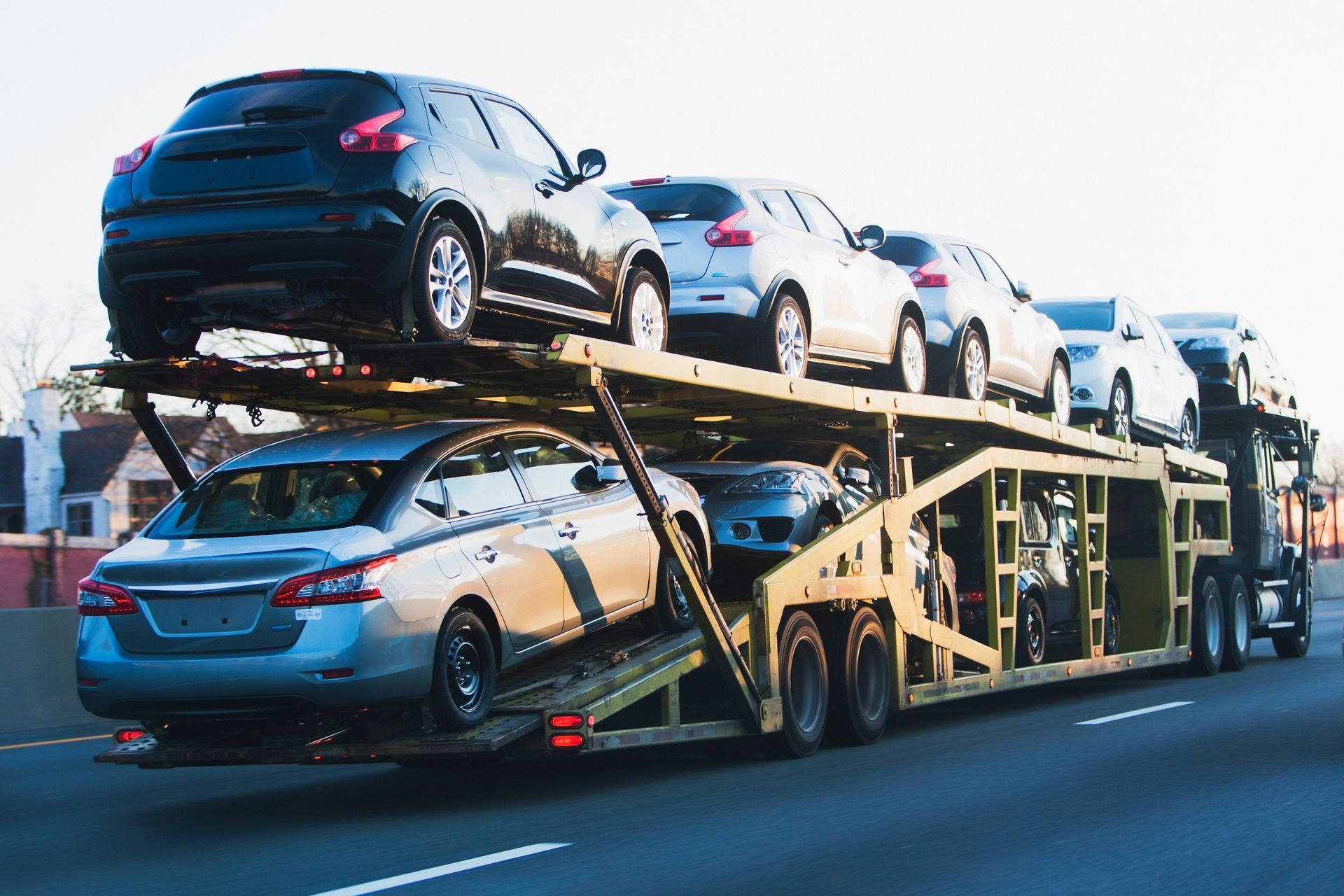 A car transporter is carrying a row of cars on top of each other on a highway.