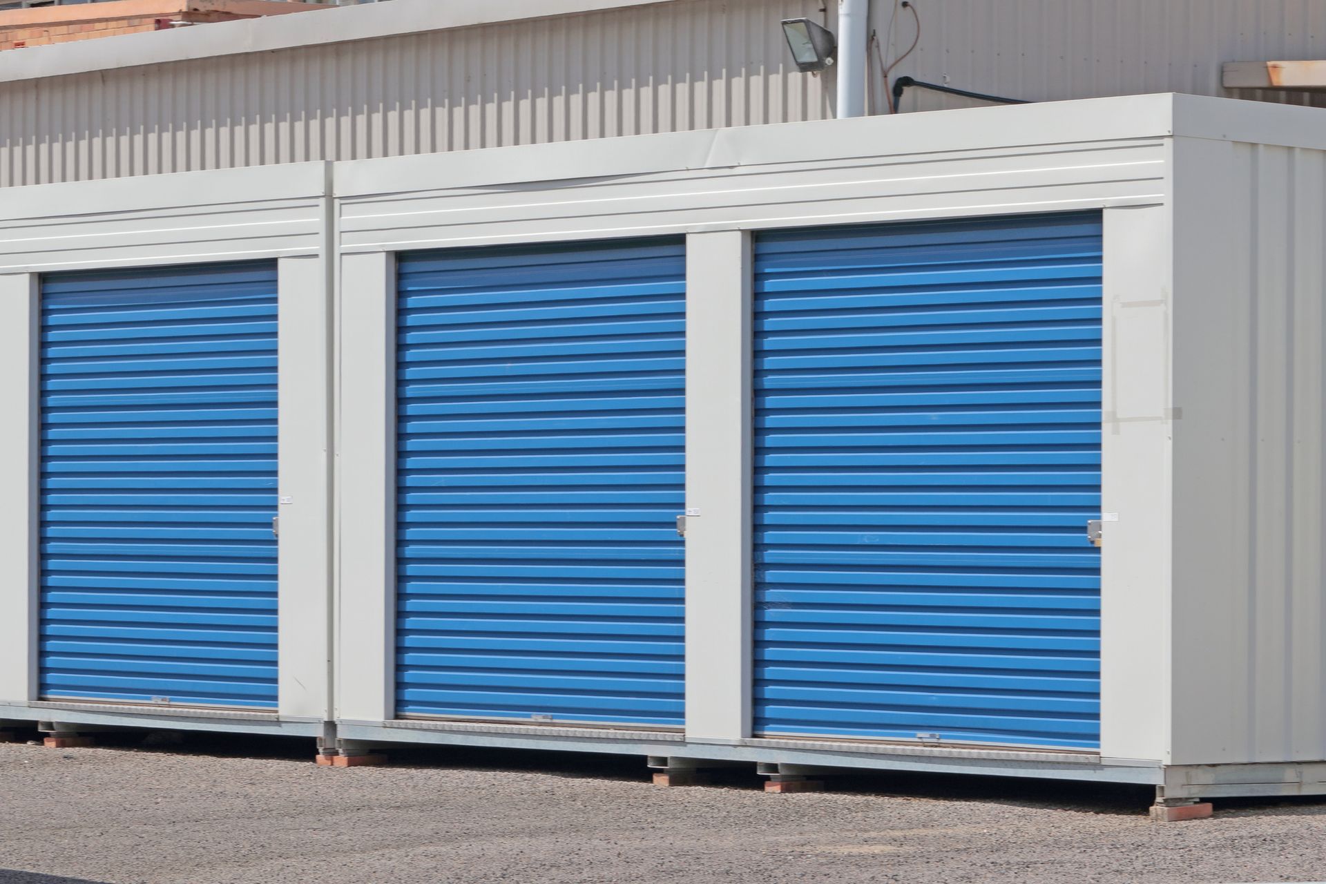 Business storage solutions with secure blue roll-up doors at modern self-storage facility units