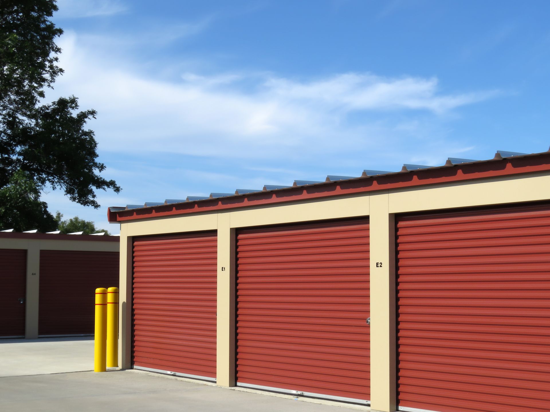 A row of red garage doors with yellow poles in front of them