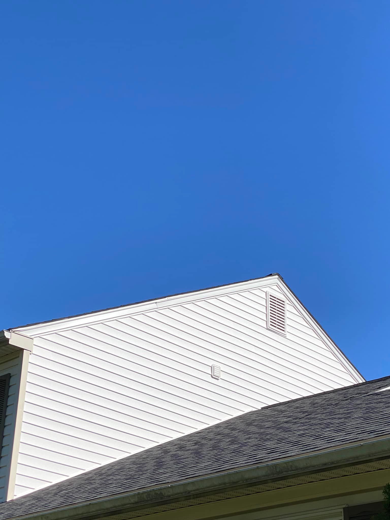 White house gable against bright blue sky.