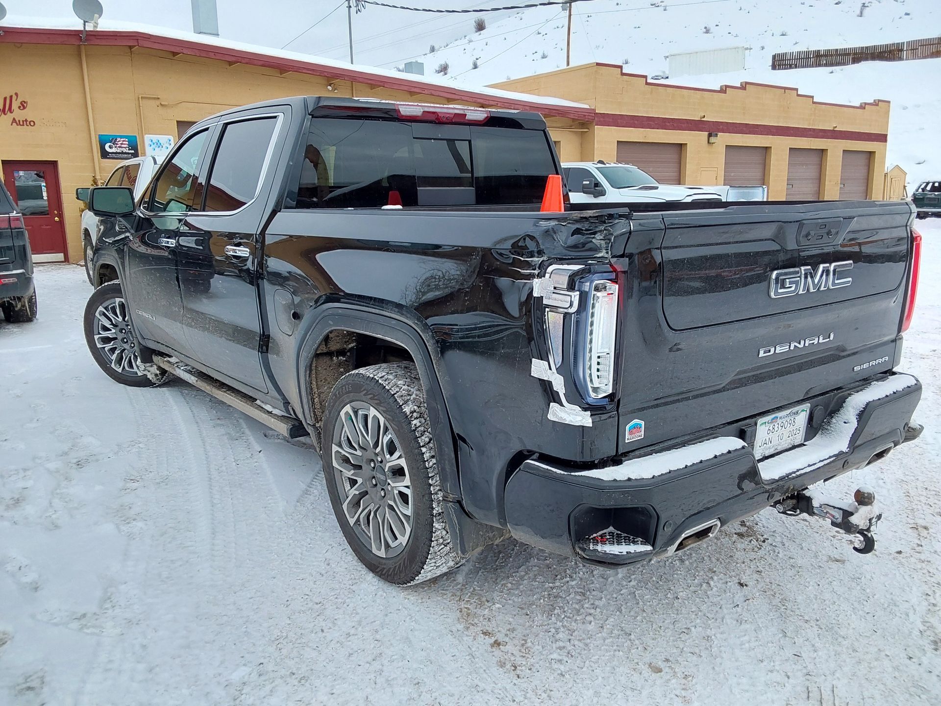 A black truck is parked in the snow in front of a building.