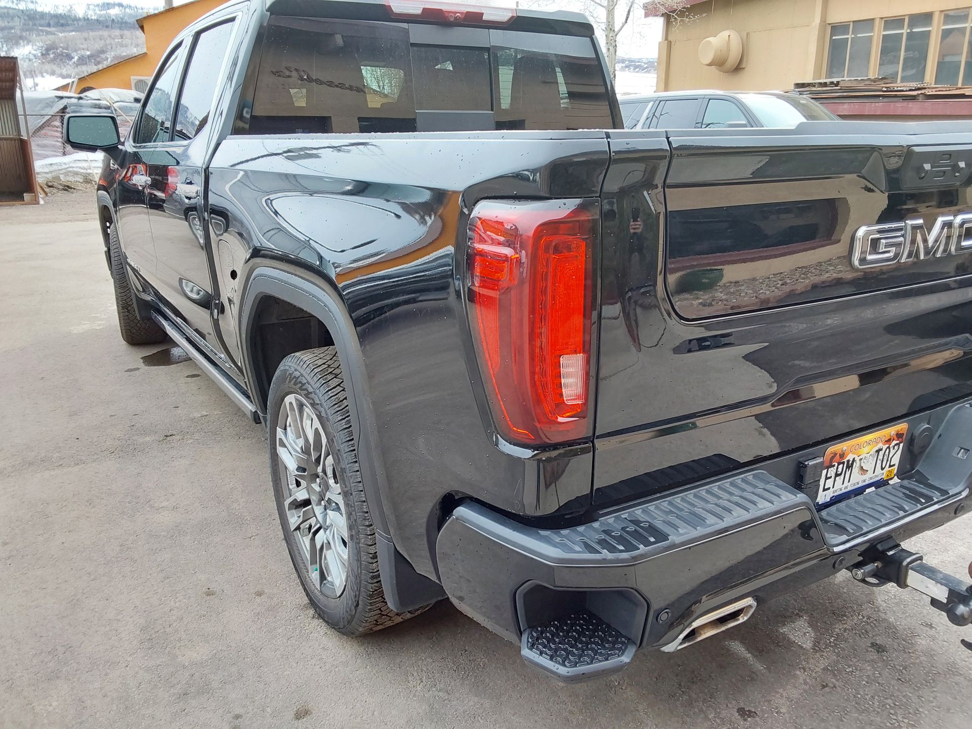 A black gmc truck is parked in front of a building.